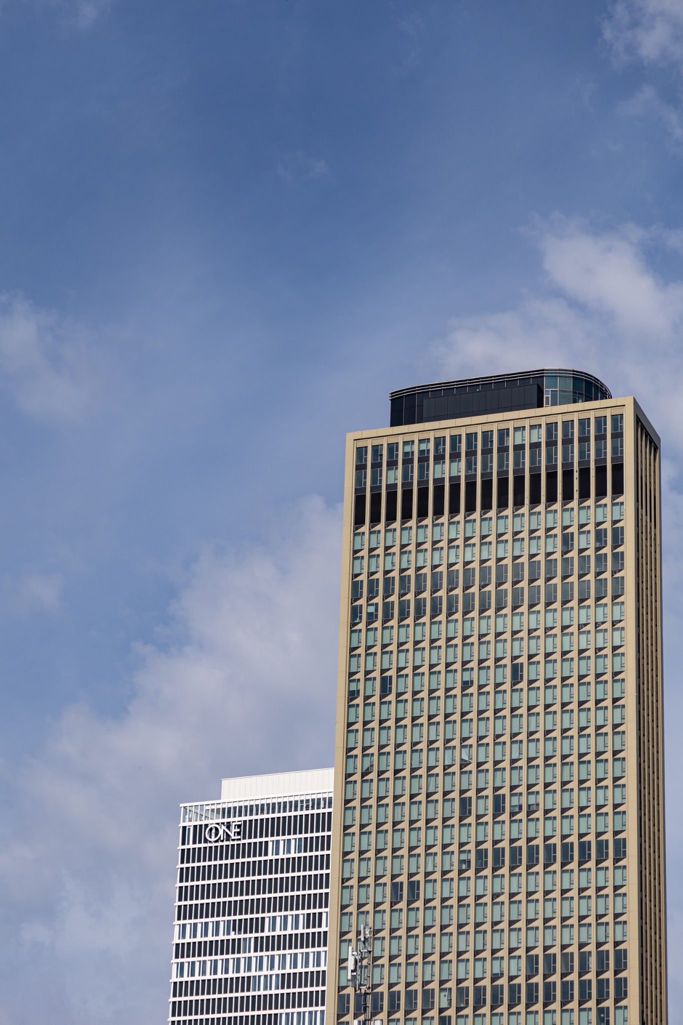 Tour moderniste dorée encadrée par un immeuble voisin